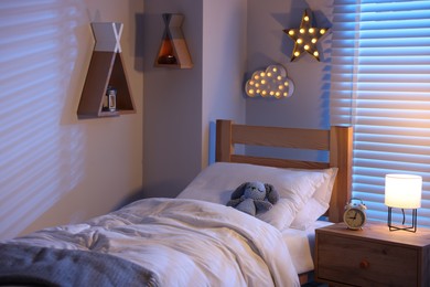 Photo of Cute toy rabbit lying in bed at home. Interior design
