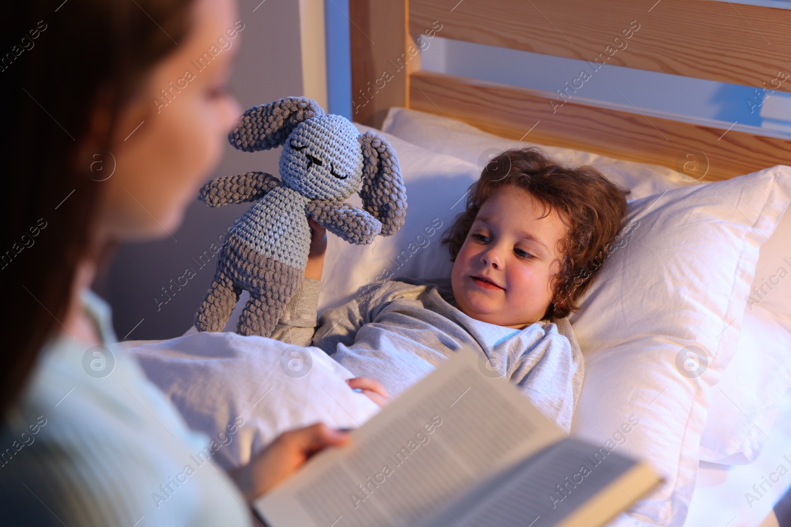 Mother reading bedtime story to her son at home, selective focus Photo of Mother reading bedtime story to her son at home, selective focus