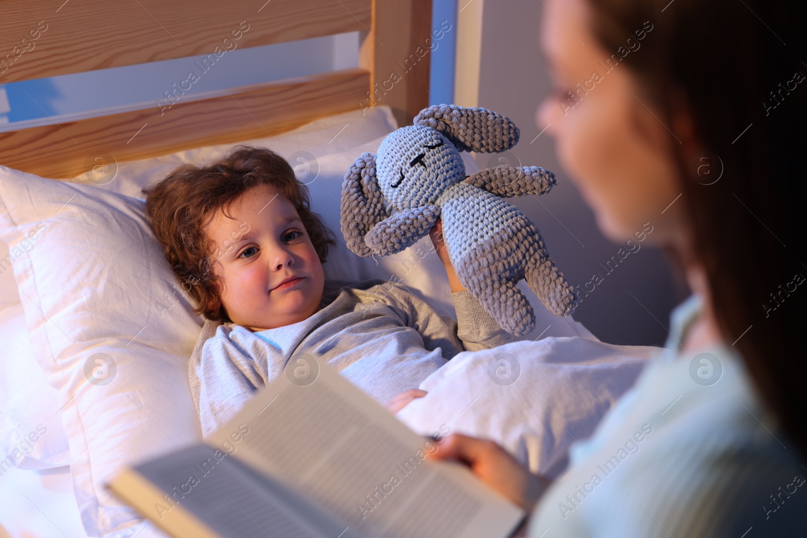 Mother reading bedtime story to her son at home, selective focus Photo of Mother reading bedtime story to her son at home, selective focus