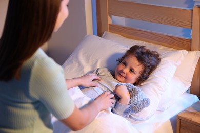 Photo of Mother putting her little son to sleep at home, selective focus. Bedtime