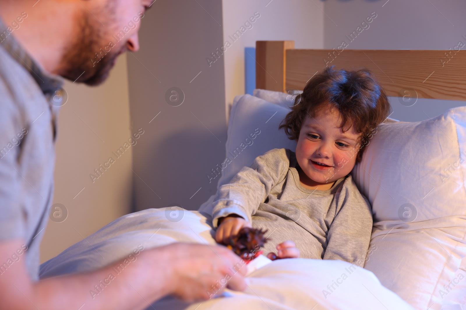 Father playing with his son before bedtime in bedroom, selective focus Photo of Father playing with his son before bedtime in bedroom, selective focus