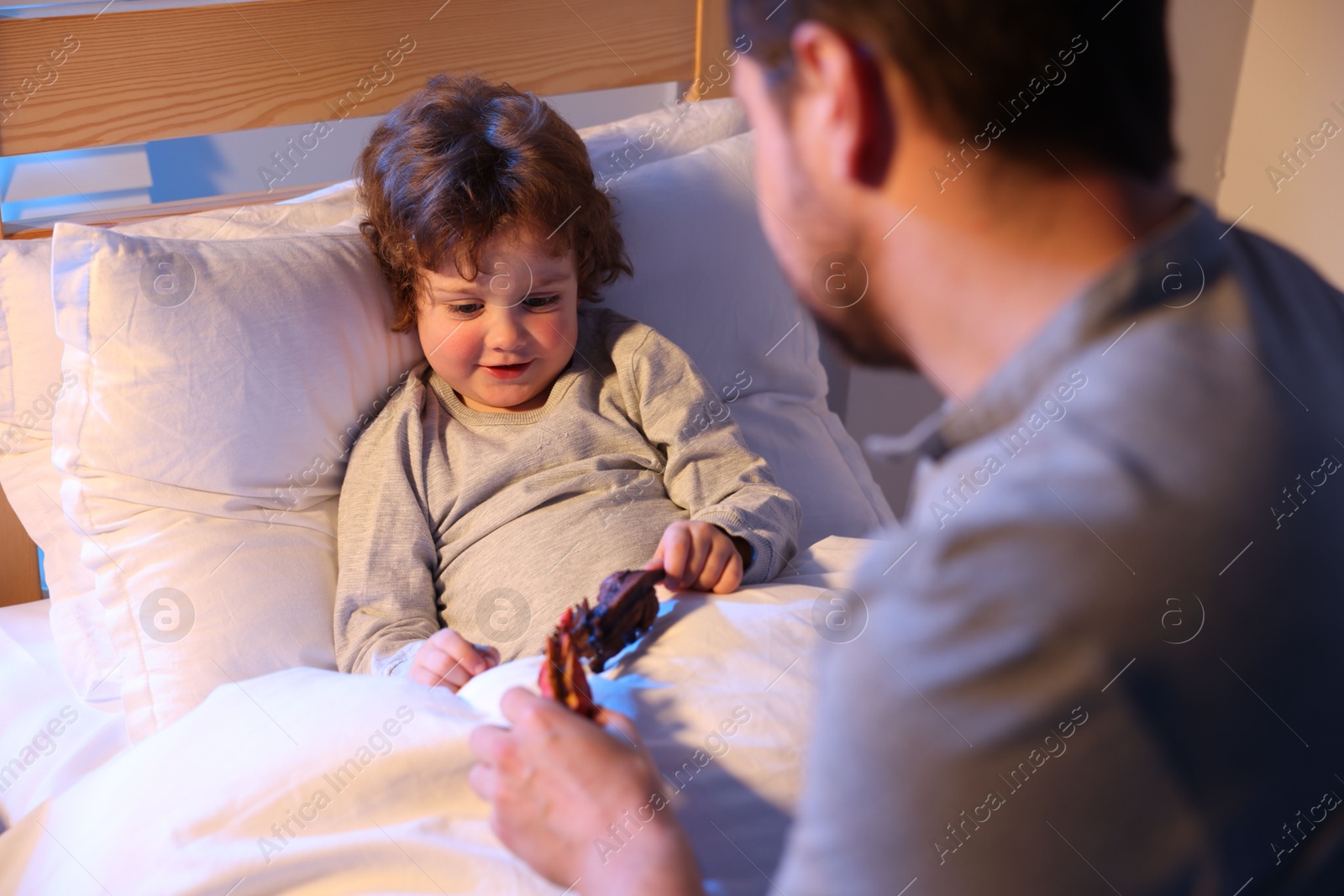 Father playing with his son before bedtime in bedroom, selective focus Photo of Father playing with his son before bedtime in bedroom, selective focus