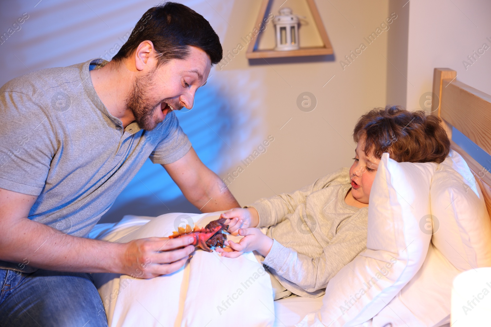 Happy father playing with his son before bedtime in bedroom Photo of Happy father playing with his son before bedtime in bedroom