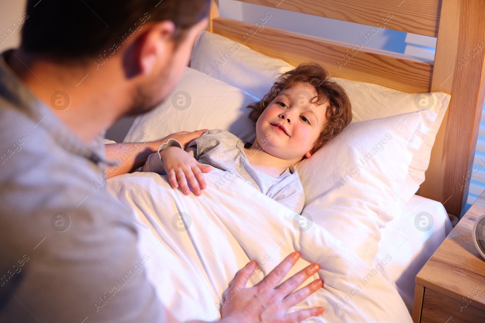 Father putting his little son to sleep at home, selective focus. Bedtime Photo of Father putting his little son to sleep at home, selective focus. Bedtime