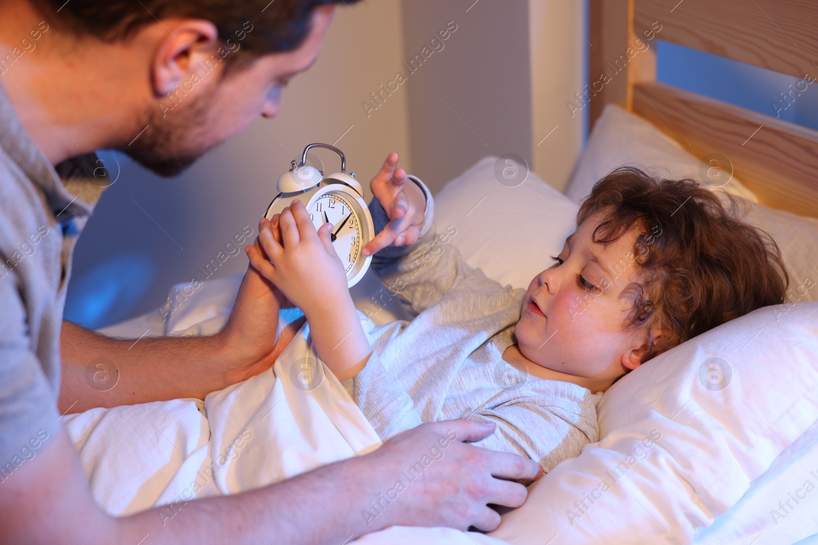 Father putting his little son to sleep at home, selective focus. Bedtime Photo of Father putting his little son to sleep at home, selective focus. Bedtime