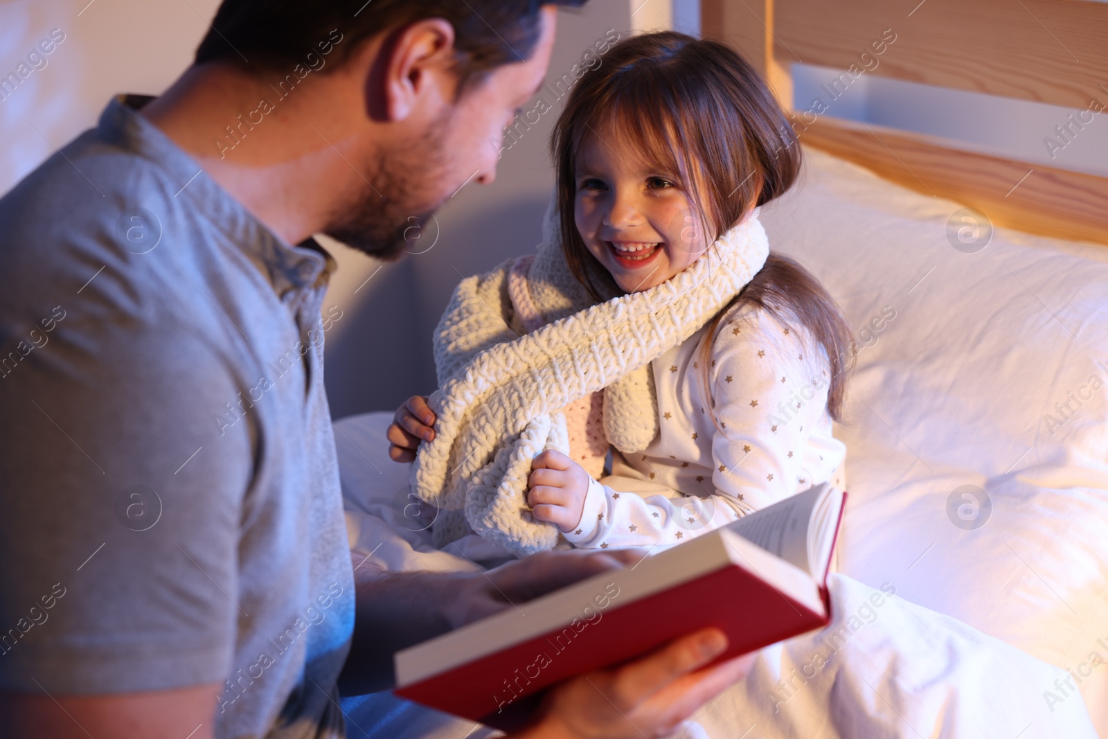 Father reading bedtime story to his happy daughter at home, selective focus Photo of Father reading bedtime story to his happy daughter at home, selective focus