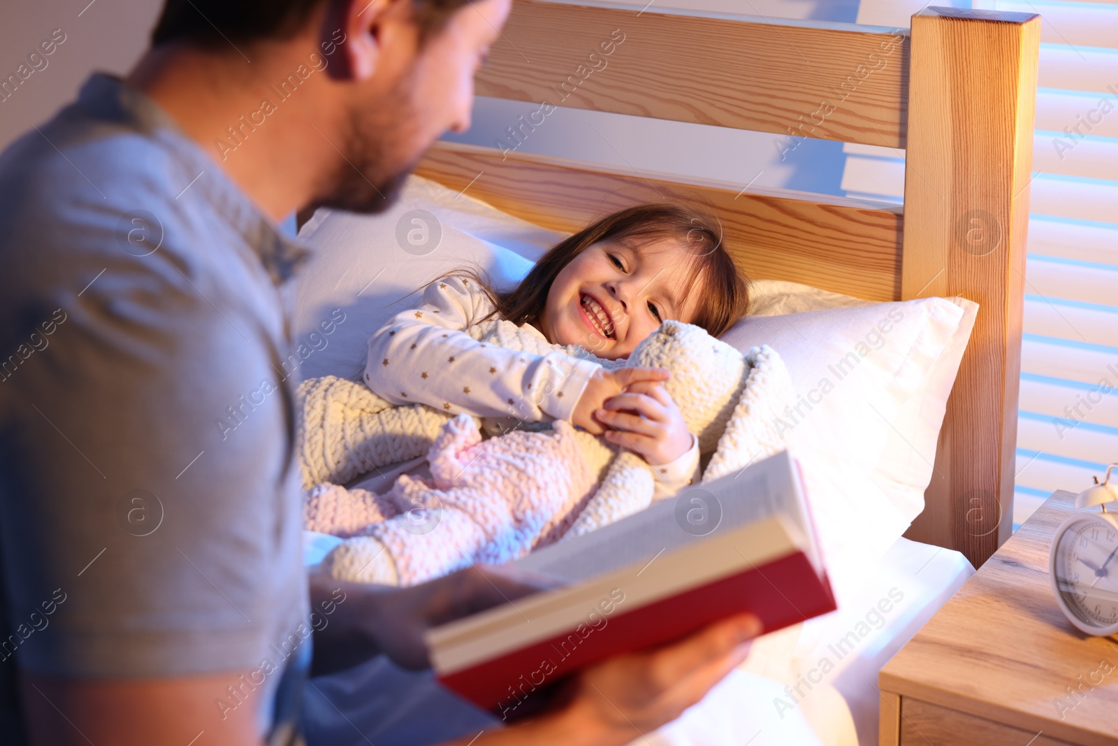 Father reading bedtime story to his happy daughter at home, selective focus Photo of Father reading bedtime story to his happy daughter at home, selective focus