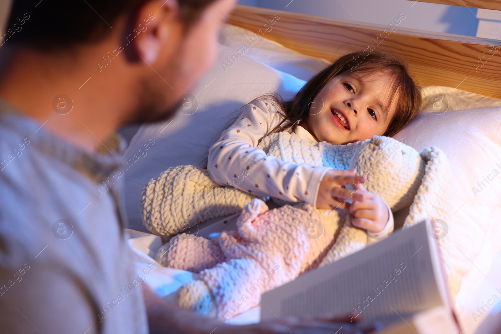 Father reading bedtime story to his happy daughter at home, selective focus Photo of Father reading bedtime story to his happy daughter at home, selective focus