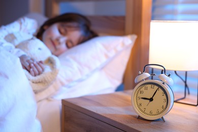 Photo of Little girl sleeping in bed at home, focus on alarm clock
