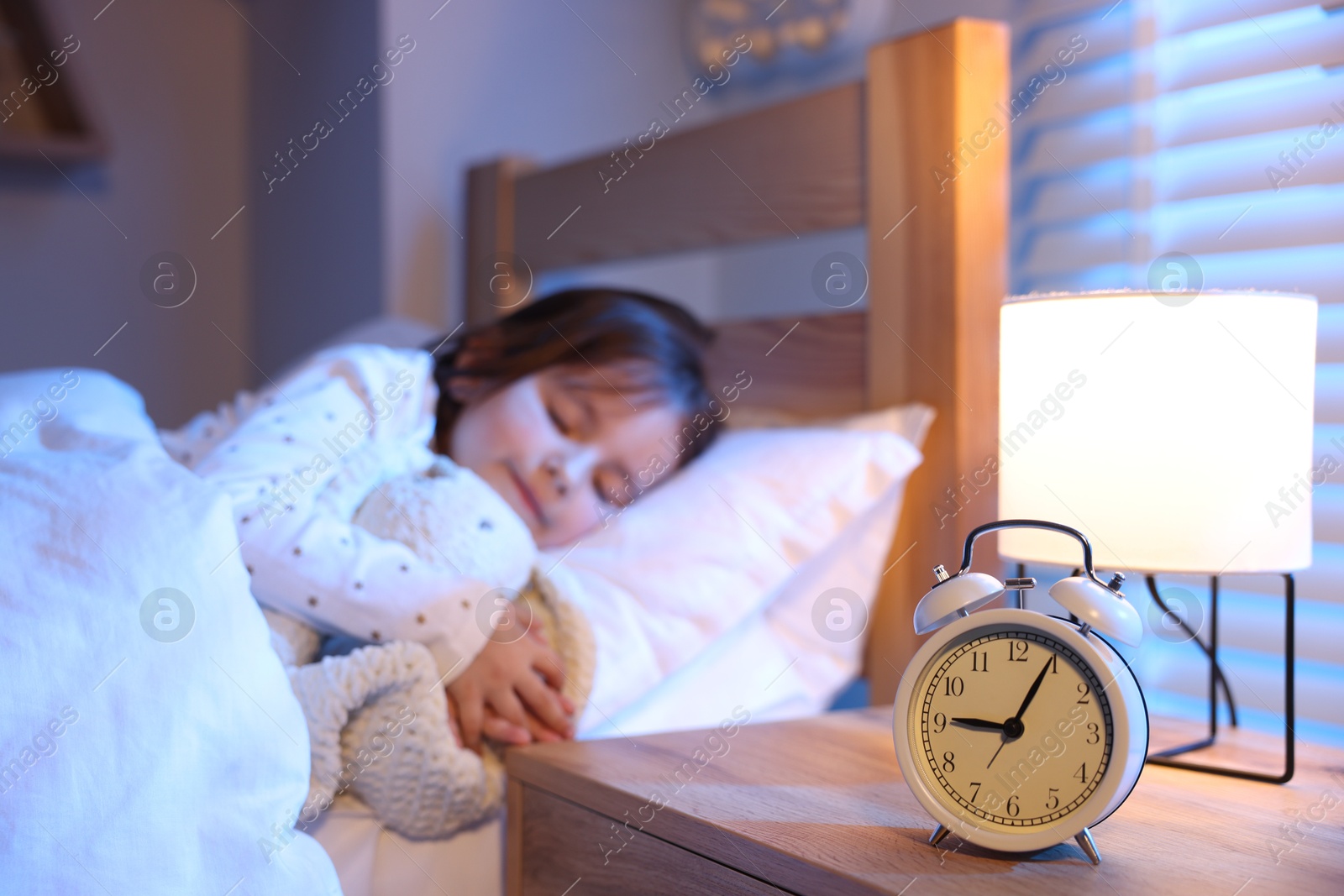 Little girl sleeping in bed at home, focus on alarm clock Photo of Little girl sleeping in bed at home, focus on alarm clock