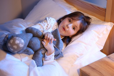 Photo of Funny little girl with toy in bed at home