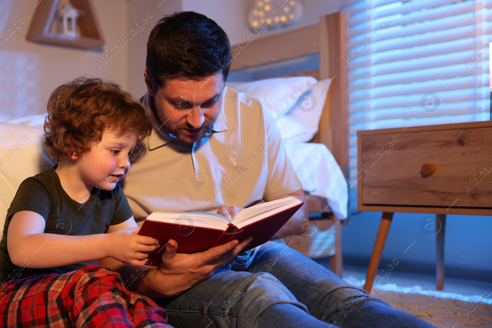 Father reading bedtime story to his son at home Photo of Father reading bedtime story to his son at home