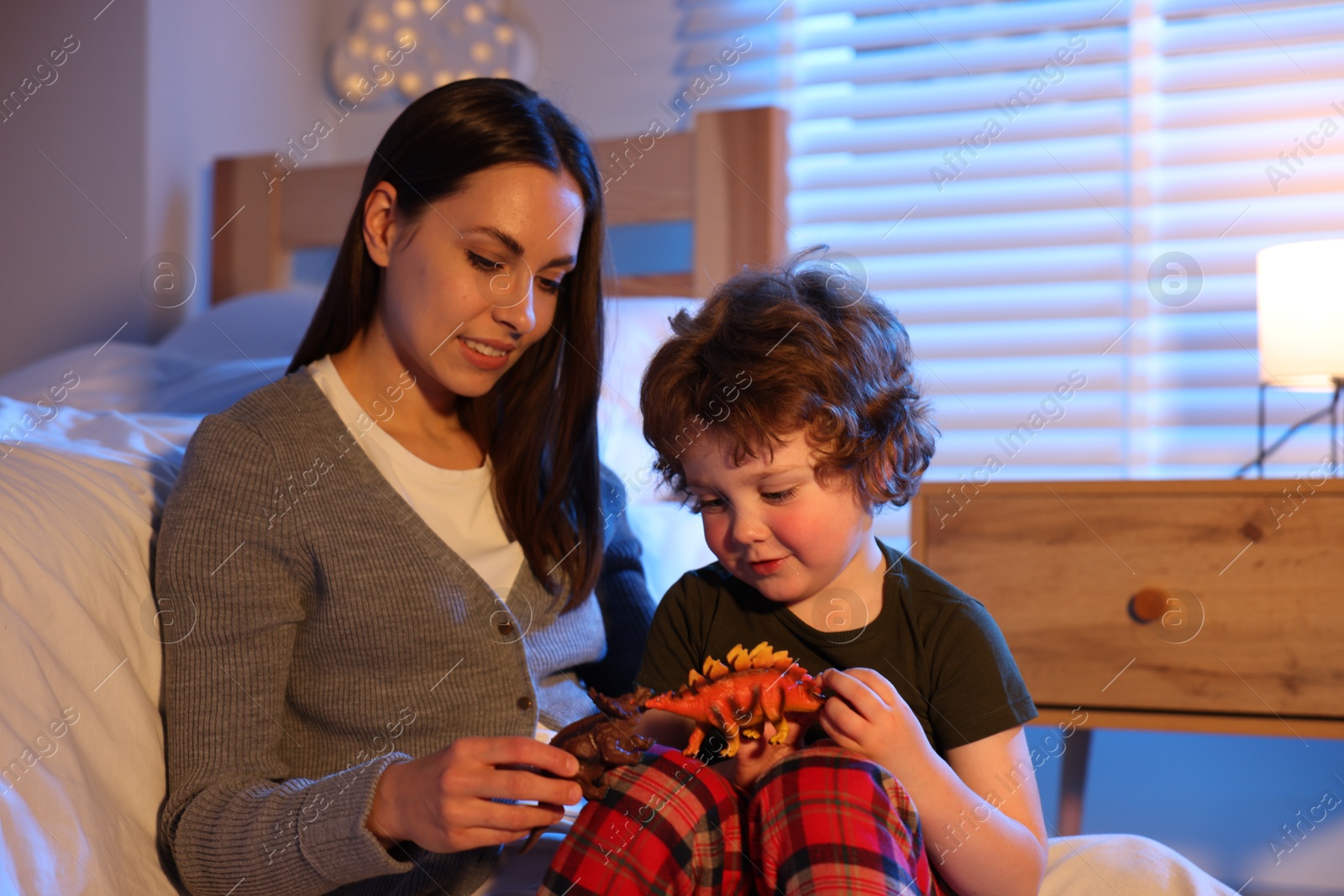 Mother playing with her son before bedtime in bedroom Photo of Mother playing with her son before bedtime in bedroom