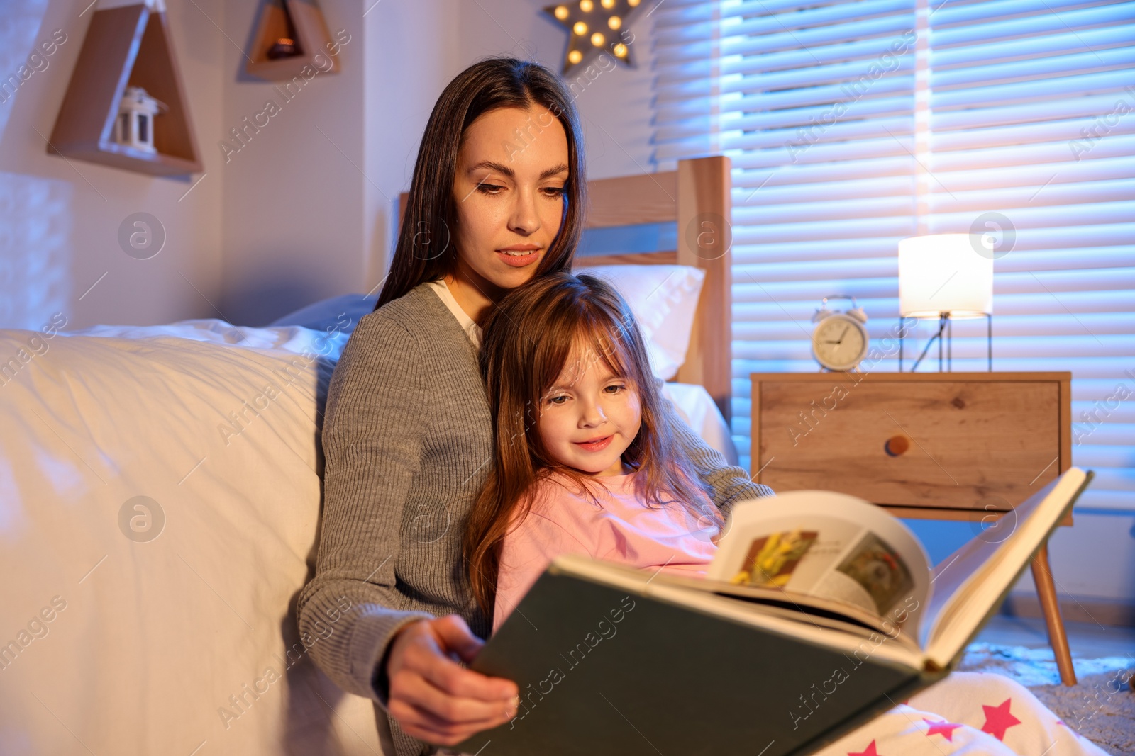 Mother reading bedtime story to her daughter at home Photo of Mother reading bedtime story to her daughter at home