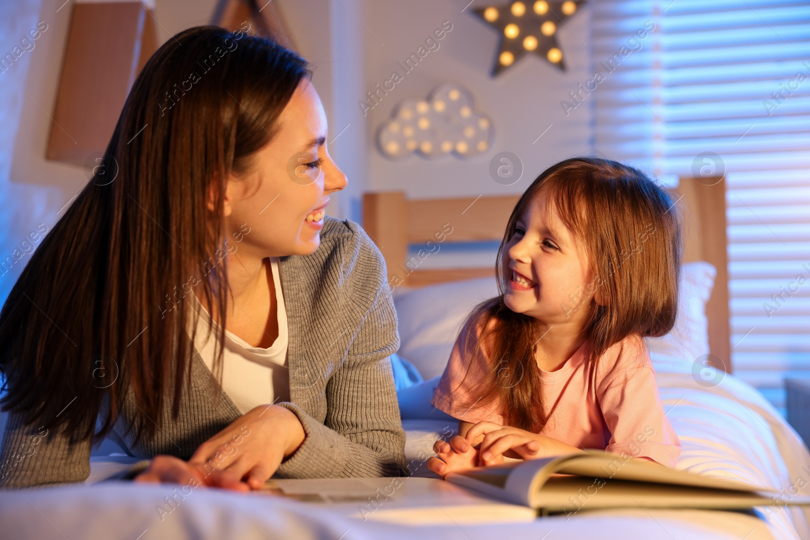 Smiling mother reading bedtime story to her daughter at home Photo of Smiling mother reading bedtime story to her daughter at home