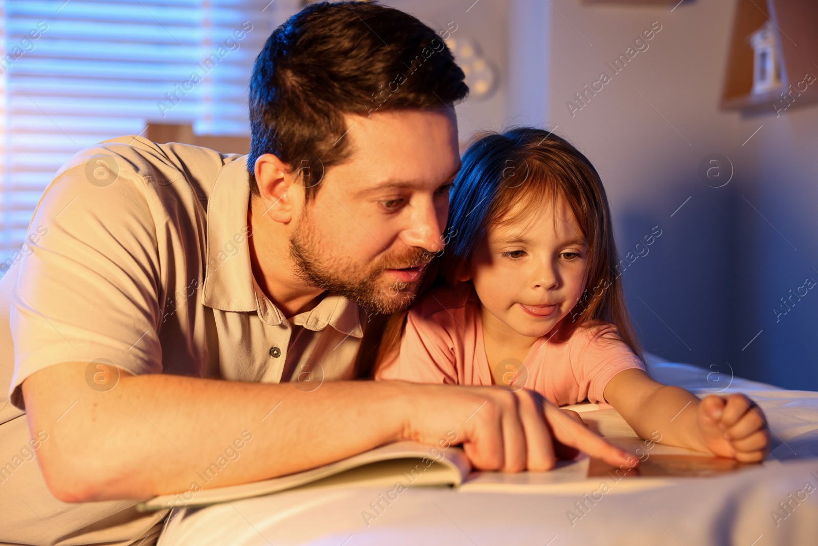 Father reading bedtime story to her daughter at home Photo of Father reading bedtime story to her daughter at home
