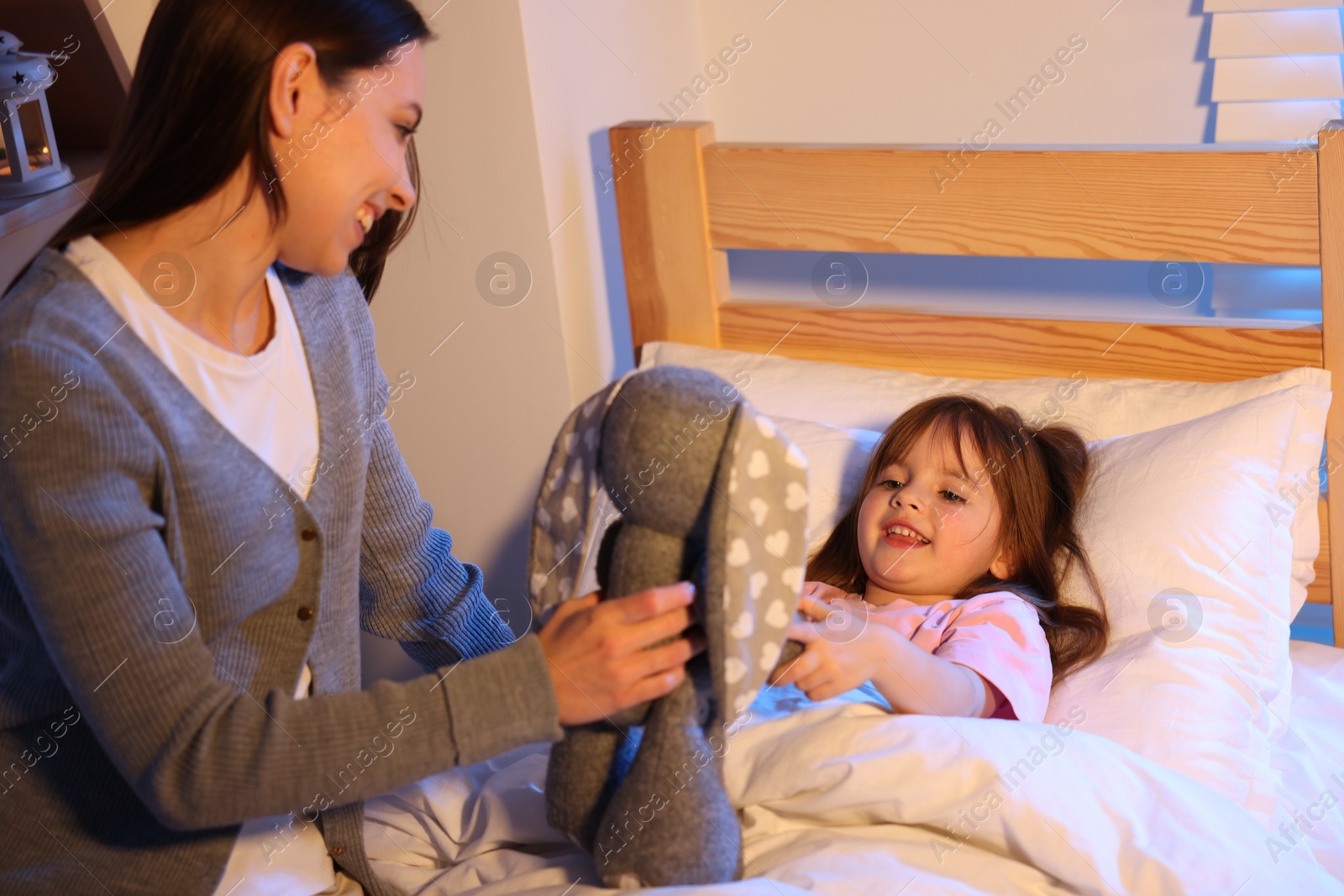 Happy mother and her daughter playing before bedtime in bedroom Photo of Happy mother and her daughter playing before bedtime in bedroom