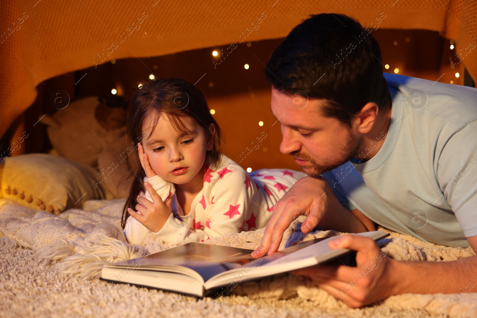 Father reading bedtime story to his daughter on floor at home Photo of Father reading bedtime story to his daughter on floor at home