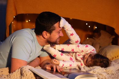 Photo of Happy father having fun with his daughter before bedtime at home