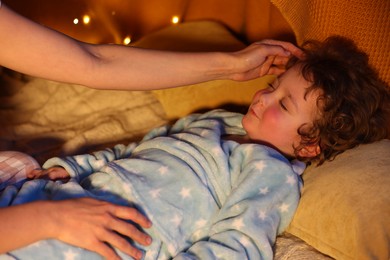 Photo of Mother putting her little son to sleep at home, closeup. Bedtime