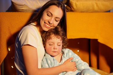 Photo of Happy mother and her sleepy son at home. Bedtime