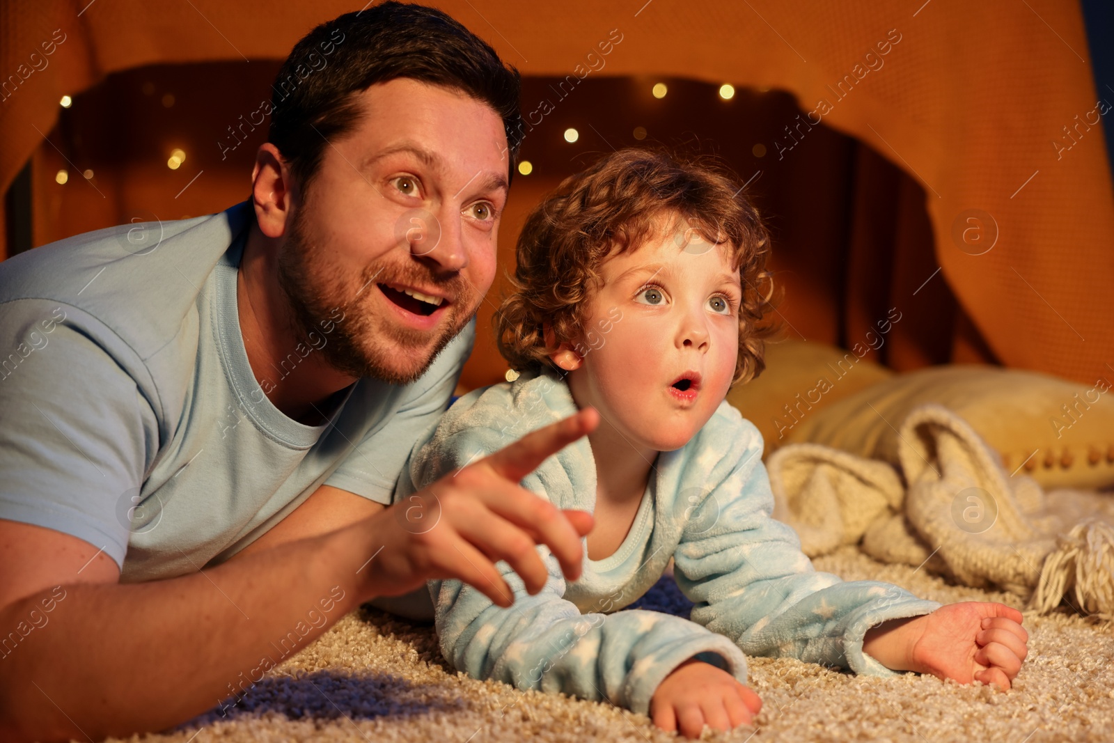 Happy father and his son pointing at something at home. Bedtime Photo of Happy father and his son pointing at something at home. Bedtime