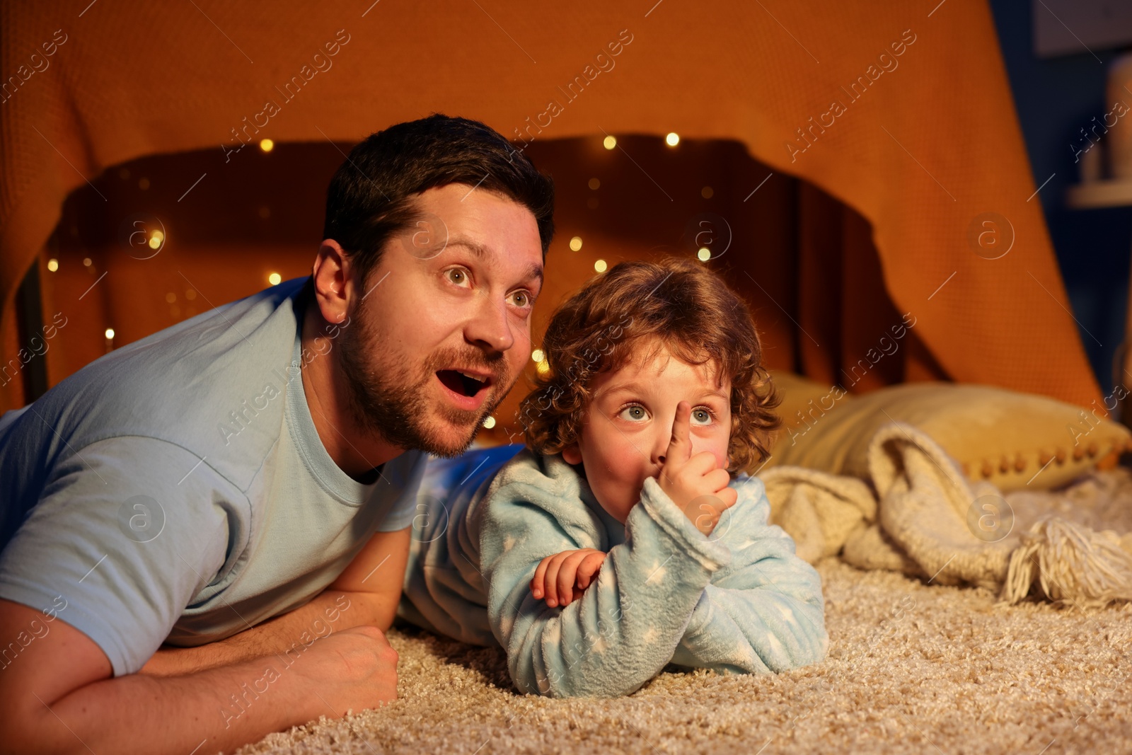 Happy father and his son looking at something at home. Bedtime Photo of Happy father and his son looking at something at home. Bedtime
