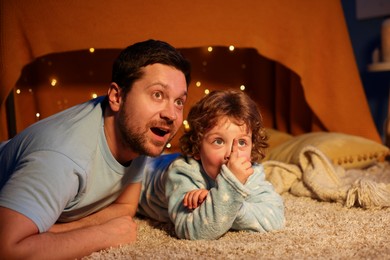Photo of Happy father and his son looking at something at home. Bedtime