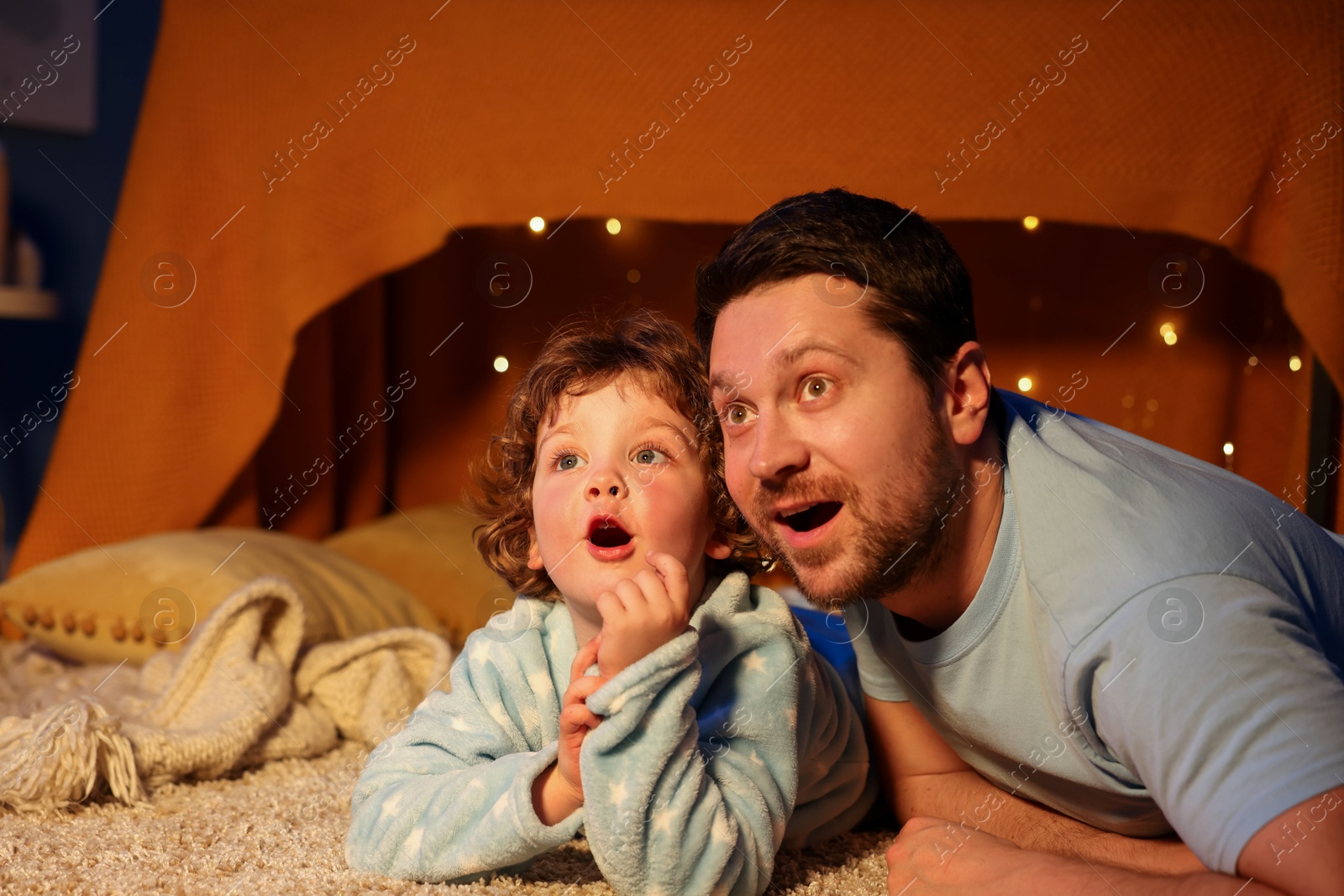 Happy father and his son looking at something at home. Bedtime Photo of Happy father and his son looking at something at home. Bedtime