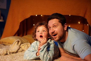 Photo of Happy father and his son looking at something at home. Bedtime