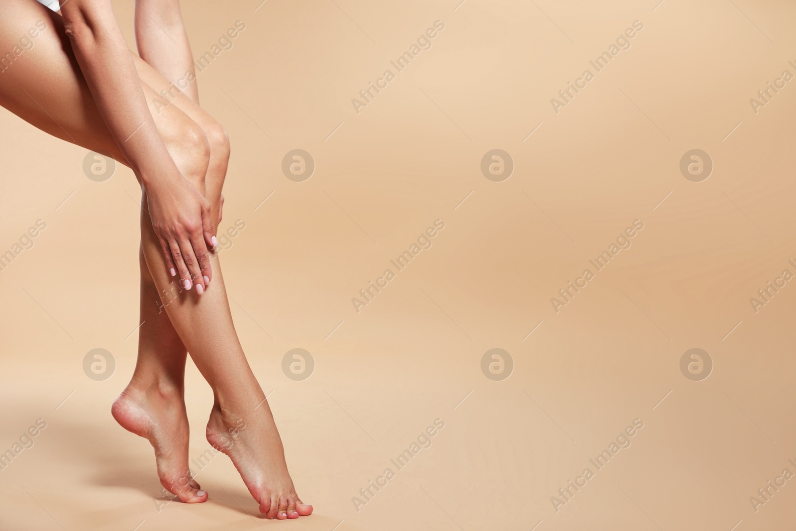Woman with beautiful smooth legs after epilation on beige background, closeup. Space for text Photo of Woman with beautiful smooth legs after epilation on beige background, closeup. Space for text