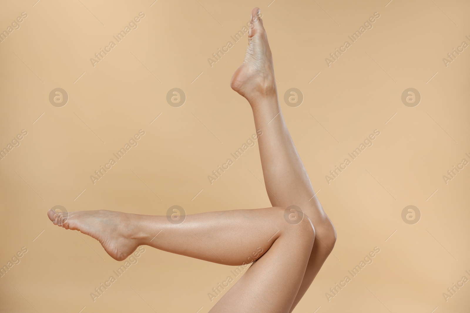 Photo of Woman with beautiful smooth legs after epilation on beige background, closeup