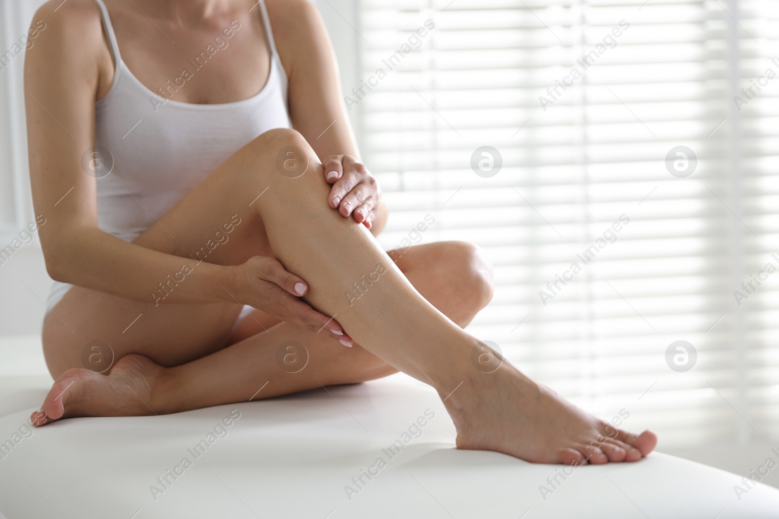 Woman with beautiful smooth legs after epilation on bed indoors, closeup. Space for text Photo of Woman with beautiful smooth legs after epilation on bed indoors, closeup. Space for text