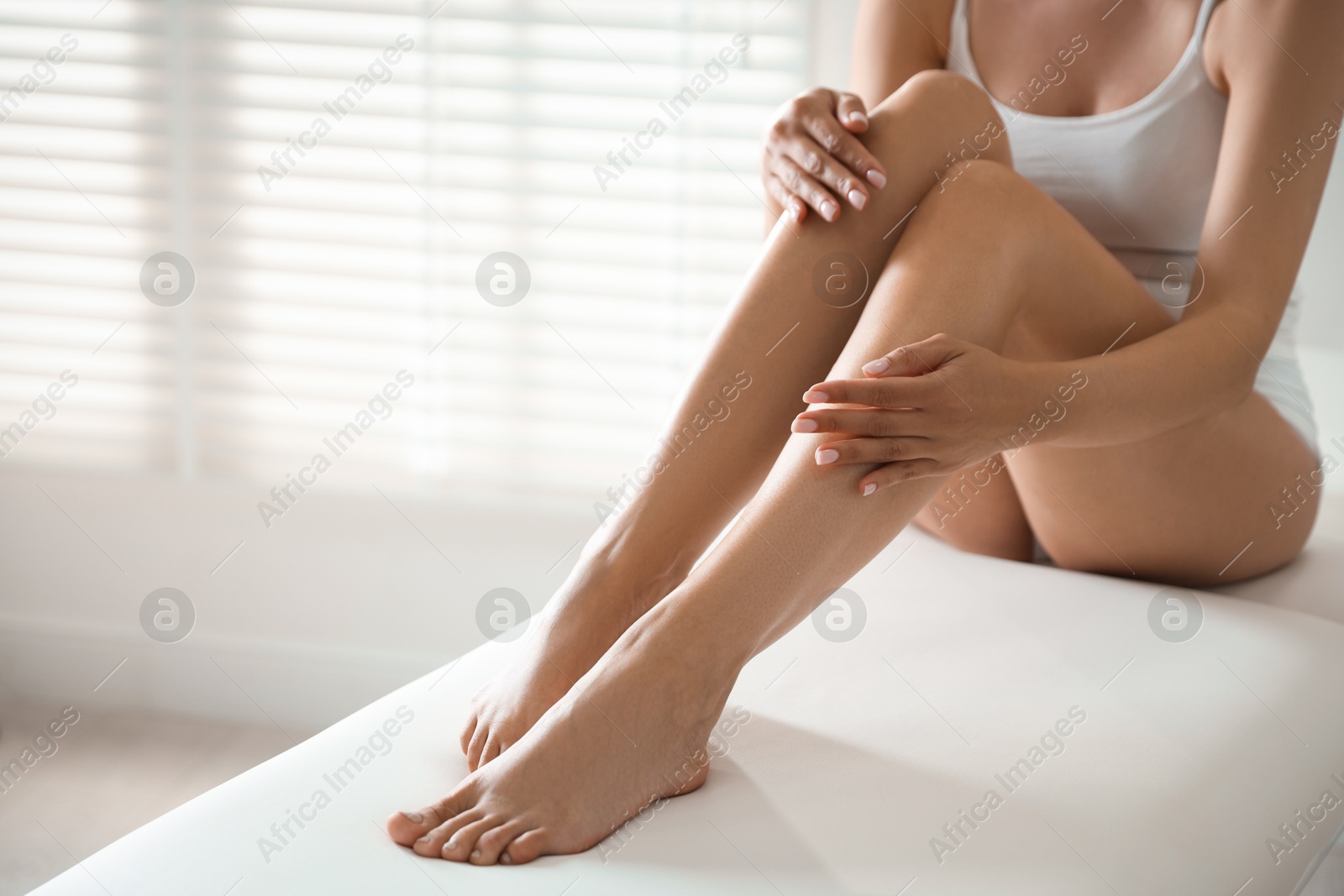 Woman with beautiful smooth legs after epilation on bed indoors, closeup. Space for text Photo of Woman with beautiful smooth legs after epilation on bed indoors, closeup. Space for text