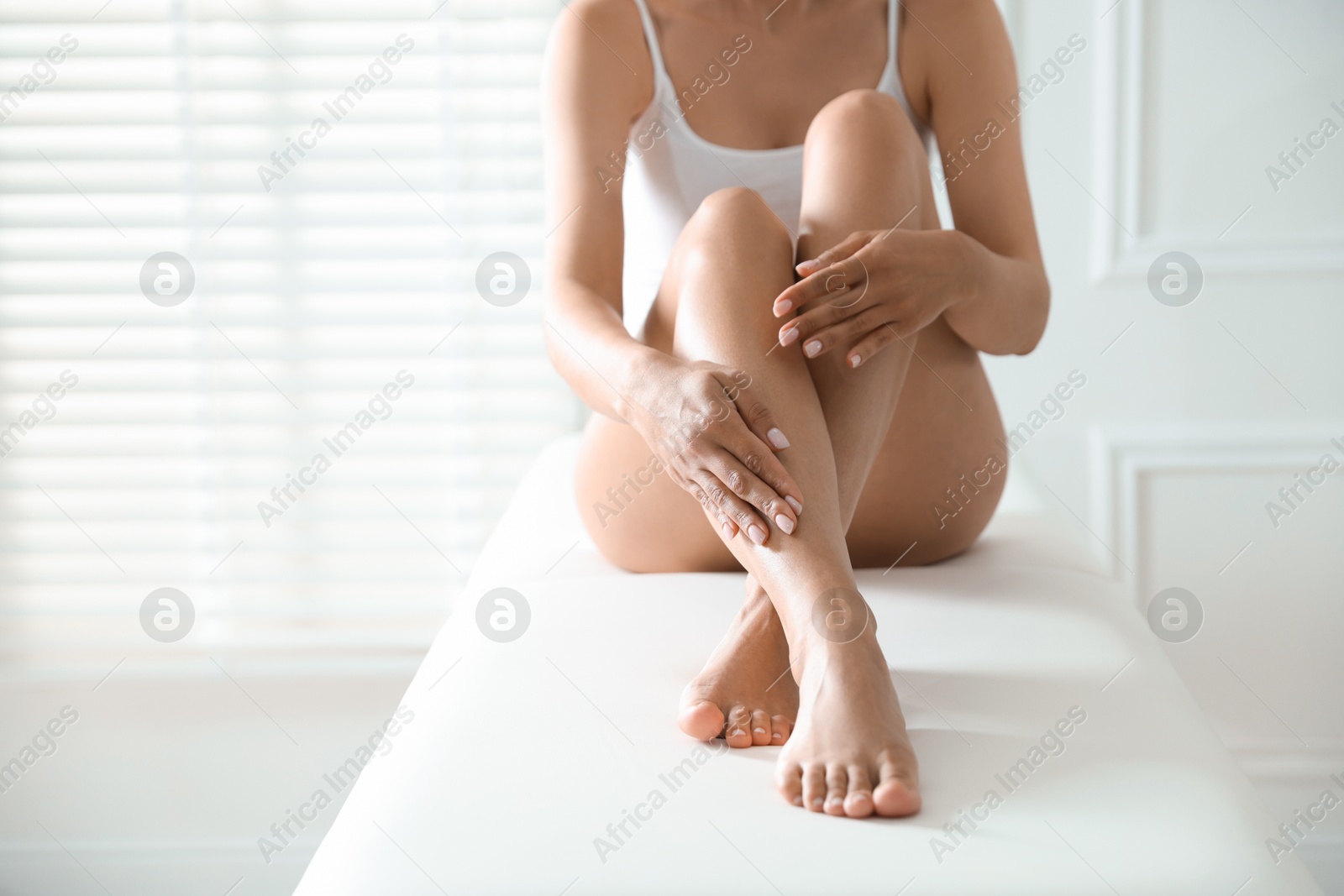 Woman with beautiful smooth legs after epilation on bed indoors, closeup. Space for text Photo of Woman with beautiful smooth legs after epilation on bed indoors, closeup. Space for text