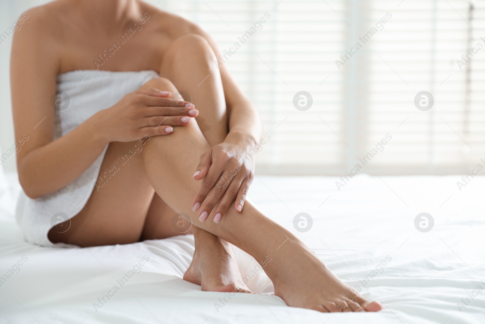 Woman with beautiful smooth legs after epilation on bed at home, closeup. Space for text Photo of Woman with beautiful smooth legs after epilation on bed at home, closeup. Space for text