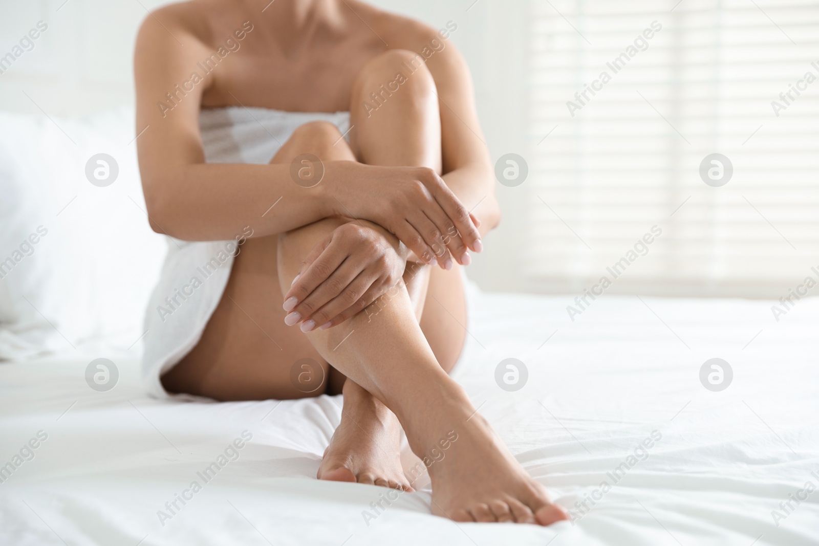 Woman with beautiful smooth legs after epilation on bed at home, closeup. Space for text Photo of Woman with beautiful smooth legs after epilation on bed at home, closeup. Space for text