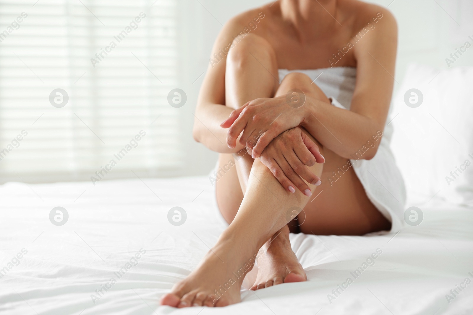 Woman with beautiful smooth legs after epilation on bed at home, closeup. Space for text Photo of Woman with beautiful smooth legs after epilation on bed at home, closeup. Space for text