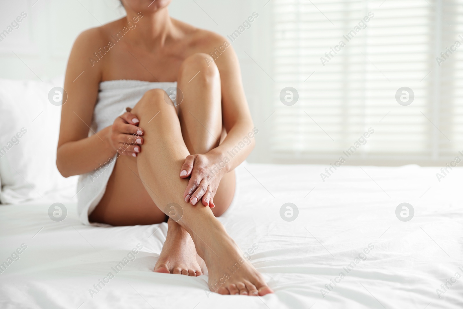Woman with beautiful smooth legs after epilation on bed at home, closeup. Space for text Photo of Woman with beautiful smooth legs after epilation on bed at home, closeup. Space for text