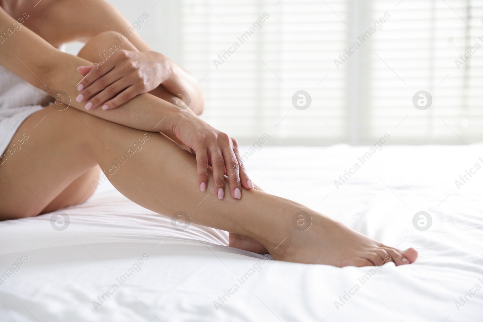 Woman with beautiful smooth legs after epilation on bed at home, closeup. Space for text Photo of Woman with beautiful smooth legs after epilation on bed at home, closeup. Space for text