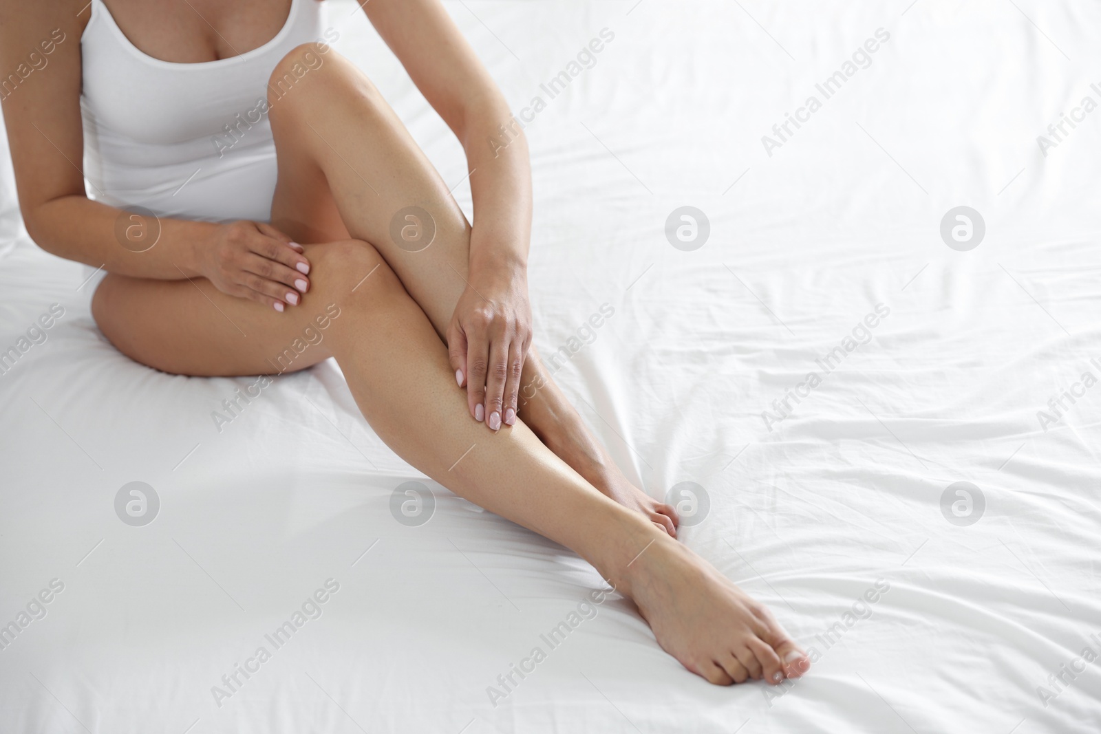 Woman with beautiful smooth legs after epilation on bed at home, closeup. Space for text Photo of Woman with beautiful smooth legs after epilation on bed at home, closeup. Space for text