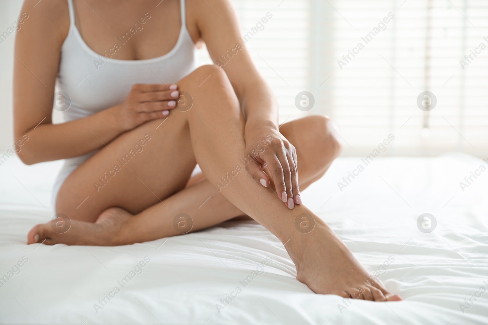 Woman with beautiful smooth legs after epilation on bed at home, closeup Photo of Woman with beautiful smooth legs after epilation on bed at home, closeup