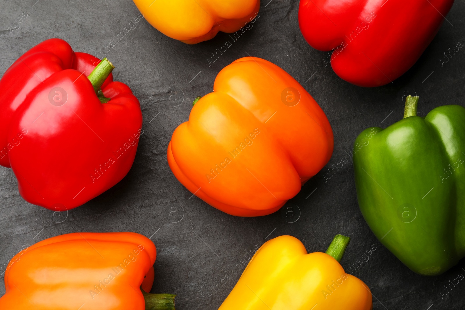Fresh colorful bell peppers on black textured table, flat lay Photo of Fresh colorful bell peppers on black textured table, flat lay