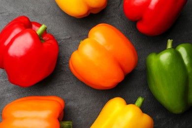 Photo of Fresh colorful bell peppers on black textured table, flat lay