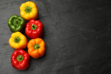 Photo of Fresh colorful bell peppers on black textured table, flat lay. Space for text