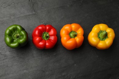 Photo of Fresh colorful bell peppers on black textured table, flat lay