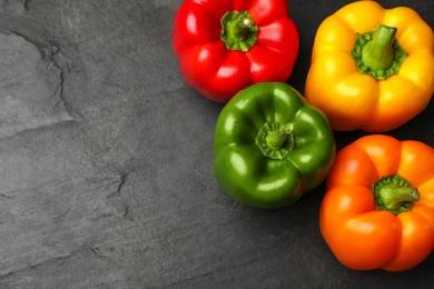 Photo of Fresh colorful bell peppers on black textured table, flat lay. Space for text