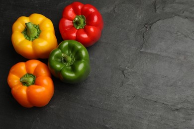 Photo of Fresh colorful bell peppers on black textured table, flat lay. Space for text