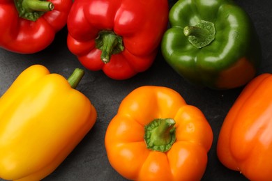 Photo of Fresh colorful bell peppers on dark gray table, flat lay