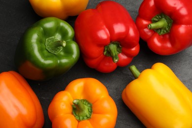 Photo of Fresh colorful bell peppers on dark gray table, flat lay